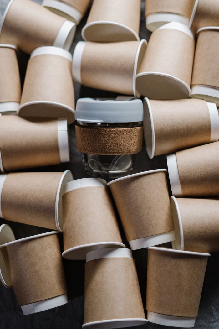 An artistic flat lay of recyclable paper coffee cups surrounding a glass jar promoting zero waste lifestyle.